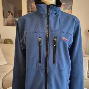 Peak Performance herrjacka * stl M - Skickar gärna foton till dig. Snygg softshell jacka i blått från Peak Performance. Jättebra skick! Ser inga skavanker.  * Alla dragkedjor är hela och det finns flera fickor.  * Hög krage * Gore windstopper membran. * Storlek M,  * Bröst: ca 55 cm mätt armhåla till armhåla * Nacke till ryggslut exkl krage: ca 66 cm * Innerärm: ca 56 cm. * Axlar, söm till som: ca 48cm.  Djur och rökfritt hem. Se bilder och förstora då de ingår i beskrivningen. Se gärna mina övriga annonser.