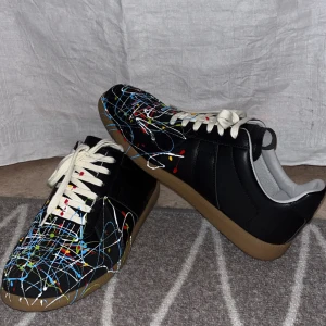 (Intressekoll) Maison Margiela svarta sneakers med färgstänk - Intressekoll på dessa svarta Maison Margiela paintsplatters. Tveka inte och skicka ett meddelande för byte eller en go peng. Använda 3-5 gånger typ. Priset är ej hugget i sten 