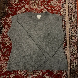 Grå stickad tröja från H&M  - Mysig grå stickad tröja från H&M i storlek XL. Tröjan har rund halsringning, långa ärmar och breda ribbade muddar vid ärmslut och nederkant. Perfekt för lager-på-lager och chill dagar. Den är liten i st jag som är M passar mig, ärmarna är långa. 