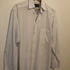 Vit klassisk skjorta från Selection S - Vit skjorta från Selection i storlek S med klassisk krage och knappstängning framtill. Skjortan har en bröstficka och långa ärmar med manschett. Materialet är mjuk bomull som känns skönt mot huden. Perfekt för dig som gillar stilrena och enkla plagg.