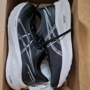 Svarta Asics GT-1000 13 löparskor - Säljer ett par tryckimpregnerade svarta Asics GT-1000 13 löparskor med vita detaljer. Perfekta för träning och löpning, med dämpande PureGel och 3D Guidance System för extra komfort. Neutral/pronation.  Använda endast några få gånger. Som nya, endast litet skrapmärke på nedersta kanten, se bild 2.