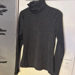 Glittrig polotop helt ny - Glittrig tight Top med snygg polokrage helt ny från H&M. Materialet är elastiskt och sticks inte. 