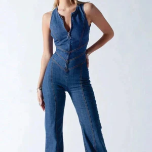 Blå denim jumpsuit med hjärtformad rygg - Snygg blå jumpsuit i denim med figurnära passform och utsvängda ben. Framsidan har en djup v-ringning med dragkedja och markerade sömmar. Baksidan har en öppen rygg i hjärtformad design som ger en unik look. Perfekt för dig som vill sticka ut. Storlek 34 (OBS, liten i storlek så skullle säga att det är en xxs). Säljer då jag ej kommer i den. Materialet är tunt och smidigt men inte så mycket stretch.