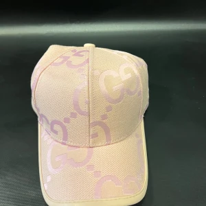 Mönstrig beige och rosa keps - Snygg keps i beige och ljusrosa med mönster. Kepsen har justerbar rem bak i ljusbeige skinn och detaljer i guld. Den är tillverkad i bomull, med exklusiv känsla och klassisk stil.