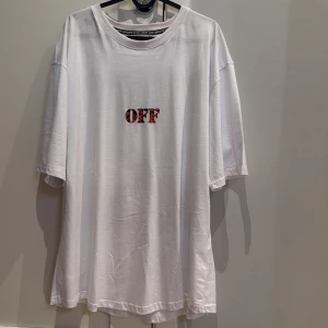 Vit Off-White t-shirt med camomönster - Säljer en vit oversized t-shirt från Off-White med färgglatt camomönstrat tryck på både bröstet och ryggen. Stort Off-White-tryck bak i blått, orange och lila. Perfekt statement-plagg för dig som gillar streetwear.