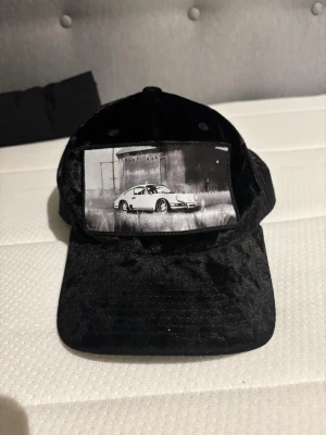 Svart sammetstruckerkeps med bilmotiv - Säljer en svart keps använd kanske 5 gånger max 