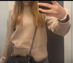 Beige stickad tröja med ribbade detaljer - Säljer en beige stickad tröja med rund hals och ribbade muddar vid ärmslut och nederkant. Tröjan har en klassisk, normal passform och är perfekt för att hålla sig varm under kyliga dagar. Enkel och stilren design som funkar till många olika outfits.