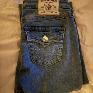 Blå jeans från True Religion - Snygga blå jeans från True Religion med bootcut-stil. De har klassiska femfickor och en tydlig logga på bakfickan. Slutsålda i storlek