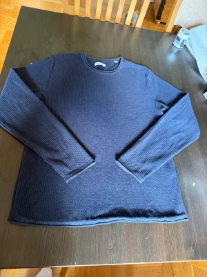 Mörkblå stickad tröja från Jack and jones - Säljer en mörkblå stickad tröja från Jack and jones. med rund hals och långärmad design. Tröjan har en snygg, diskret struktur i materialet och passar perfekt för dig som gillar stilrena och enkla plagg. Skön passform och mjukt material.