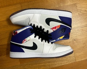 Unika Jordan 1 mid - Säljer ett par limited Air Jordan 1 Mid “Valentine’s Day Flower” (2023). Skorna har en unik design med blomstertema och genomskinlig sula. Endast testade ett par gånger och är i princip helt nya. Originala lådan medföljer ej. Ett par crease-skydd (2st) ingår. Perfekta för både samling och användning.