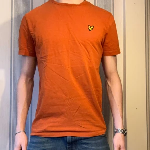 Orange t-shirt från Lyle & Scott - Snygg orange t-shirt från Lyle & Scott med klassisk rund hals och korta ärmar. Tröjan passar perfekt till Casual stilen. Mycket bra skick i storlek M