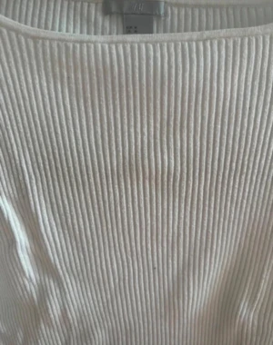 Vit ribbad långärmad tröja H&M - Säljer en vit långärmad tröja från H&M. Tröjan har ett ribbat mönster och är figurnära med rund halsringning. Perfekt att styla med jeans eller kjol. Tyvärr har tröjan ett par små svarta prickar framtill