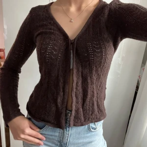 Brun stickad kofta med v-ringning - Säljer en brun stickad kofta med v-ringad hals och långärmad design. Vet inte riktigt vilken storlek men skulle söga xs och märket är mexx