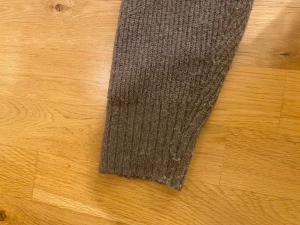 Brun ribbad kofta med knappar - Mysig brun kofta med ribbad struktur och fyra knappar framtill. Modellen har v-ringad hals och långa ärmar med breda muddar. Perfekt för lager-på-lager. Materialet känns stickat och är skön. Lapp saknas men den är i en XS.