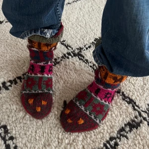 Färgglada stickade ullsockor - Unika och mysiga stickade sockor/ strumpor med coolt etno mönster. Perfekta för kalla dagar inomhus. Handgjorda i ren ull som sticks lite på bar hud, så funkar bäst med andra strumpor under. Hälen är stor och sticker ut så passformen är nästan som en innesko. Detta ger flexibelt utrymme, storleken är uppskattningsvis ca 38-40. Modellen har strl 38. Nyskick, knappt använda. 