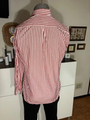 Stenströms skjorta - Snygg vintage skjorta från Stenströms med rödvita vertikala ränder och klassisk krage. Skjortan har långa ärmar med manschett och vita knappar framtill. Tillverkad i mjuk bomull som känns skön mot huden. Perfekt för dig som gillar stilrena och färgstarka plagg.