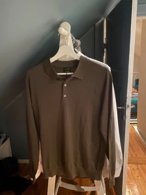 Brun pikétröja i merinoull Massimo Dutti - Snygg brun långärmad pikétröja från Massimo Dutti i mjuk merinoull. Klassisk krage och tre knappar framtill. Perfekt för dig som gillar stilrena och bekväma plagg med lite extra premiumkänsla. Den är dessutom HELT NY. Storlek M