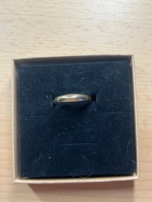 Klassisk guldfärgad ring - En stilren och enkel guldfärgad ring med rundad form. Ringen har en blank, polerad yta och passar perfekt för dig som gillar minimalistiska smycken. Levereras i en svart ask.