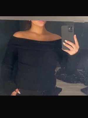 Svart offshoulder stickad topp - Snygg svart stickad topp med offshoulder-modell och långa ärmar. Storlek S