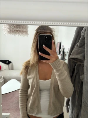 Beige ribbad kofta från vila - Snygg beige kofta från Vila i mjukt stickat material. Koftan har öppen front, långa ärmar och ribbade muddar samt nederkant. Perfekt att slänga över ett linne eller t-shirt för en chill look.