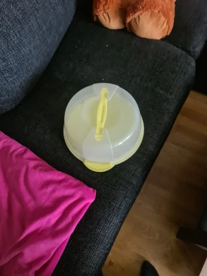 Gul kakburk med handtag i plast - Praktisk rund kakburk i genomskinlig och gul plast med smidigt handtag på locket. Perfekt för att förvara eller transportera kakor, bullar eller andra bakverk. Locket har två spännen som håller det på plats.