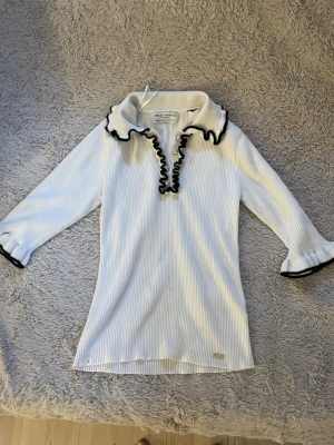 Vit ribbad topp med volang från Holly & Whyte - Jätte snygg tröja .ett hål i men syns inte när du har på den