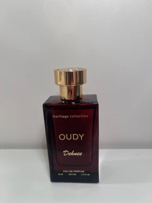 Oudy Dehnee Heritage Collection parfym - Mans parfym! Elegant Eau de Parfum från Oudy Heritage Collection. Flaskan är mörkröd med guldfärgad kork och detaljer. Rektangulär form i glas med exklusiv känsla. Rymmer 80 ml och har en lyxig design som sticker ut på parfymhyllan.