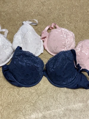 Spetsbhar i vitt, rosa och marinblått - Säljer ett set med bhar i tre färger: vitt, ljusrosa och marinblått. Alla bhar har vacker spetsdetalj och justerbara axelband. Perfekt för dig som gillar en feminin och stilren look. Kuporna är lätt vadderade för extra komfort. Den vita är använd 1 gång därför lite missfärgad på kanten då jag hade brun utan sol men annars aldrig använt nån av dem. Brun utan solen kan gå bort med något slags medel men inget jag provat ännu utan vill man ha dom så får man prova själv!😊Man köper alla!