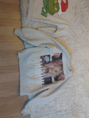 Beige sweatshirt med Home Alone-tryck och Grinch från Cubus - Cool beige sweatshirt med stort tryck från filmen Home Alone på framsidan. Tröjan har rund hals och långa ärmar. Perfekt för dig som gillar filmklassiker och vill sticka ut med ett unikt motiv. 250 /2st eller 150 per st