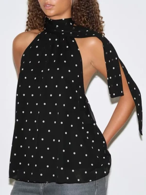 Svart prickig halterneck-top - Snygg svart halterneck-top med vita prickar och knytband i nacken från Gina tricot. Toppen är ärmlös och har öppen rygg, vilket ger en cool och trendig look. Aldrig använd!