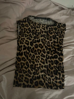 Leopardmönstrad topp från Black Label - Snygg leopardmönstrad topp från The Black Label Collection i storlek XS. Toppen har en klassisk rund halsringning och är ärmlös, perfekt för att sticka ut med ett djurmönster. Materialet känns mjukt och stretchigt, vilket gör den bekväm att bära.