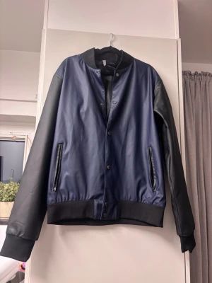 Tretorn jacka – Vattentät bombermodell storlek M - Säljer en fin regnjacka från Tretorn i bombermodell.   Jackan är mörkblå med svarta ärmar. • Vattentät • Design: Klassisk modell med knappar och fickor med dragkedja. • Skick: Mycket fint skick, knappt använd. • Storlek: Medium  En perfekt jacka för både höst och vår!  Nypris 1000:-