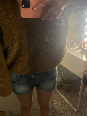 Brun teddyjacka med dragkedjor - Mysig brun teddyjacka i fluffigt material med två sneda dragkedjor framtill. Jackan har en loose passform och lång ärm, perfekt för att hålla värmen. 