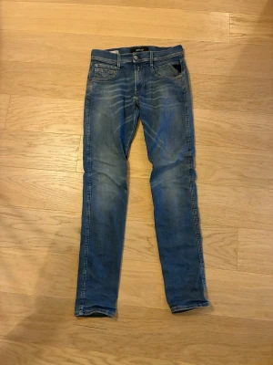 Blå slim fit jeans från Replay hyperflex - Snygga blå slim fit jeans från Replay med klassisk femficksdesign och diskreta slitningar framtill. Jeansen har normal midja, dragkedjegylf och är tillverkade i ett mjukt denimtyg som ger en skön passform hyperflex. Perfekta 