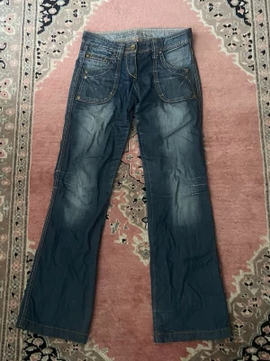 Blå bootcut jeans med coola fickor - Snygga blå bootcut jeans med coola fickor. Säljer då de är för små i midjan för mig men är perfekt längd för mig som är 163 cm lång.💕midjemått: 37 cm, innerbenslängd: 80 cm.