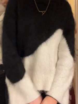 Svartvit stickad tröja med vågig kant - Säljer en snygg stickad tröja i svart och vitt med unik vågig färgdelning. Tröjan har lång ärm, rund halsringning och är gjord i ett mjukt, fluffigt material som känns riktigt cozy. Perfekt för dig som vill ha något trendigt och bekvämt i garderoben.