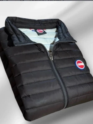 Svart dunväst från Colmar - Snygg svart dunväst från Colmar med quiltad design och två dragkedjeförsedda fickor framtill. Västen har en hög krage och Colmar-logga på bröstet. Perfekt för lager-på-lager och håller dig varm under kyliga dagar. Har en liten defekt längst ner på västen