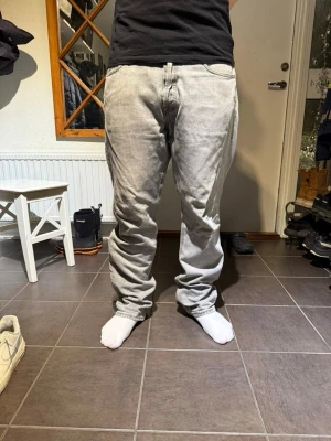 Jack and Jones 501 - Säljer ett par grå Jack and Jones 501 jeans med klassisk rak passform och femficksmodell. Jeansen är ganska slitna längs ned vid fötterna, det var också ett litet hål i skrevet men det är lagar så de syns inte.Perfekta för dig som gillar en tidlös och avslappnad stil. W32 L32