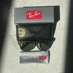 Ray-Ban Wayfarer Solglasögon - Riktigt snygga solglasögon från Ray-Ban. Aldrig använda. Tillbehör medföljer. Glaset har en grön tint. Fraktas samma dag som köp!