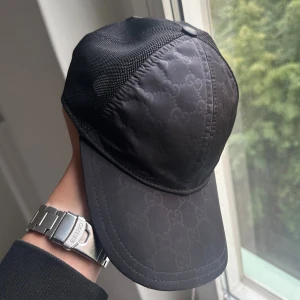 (Äkta) Svart Gucci Nylon Keps - Riktigt clean och diskret keps från Gucci. Den här modellen säljs inte längre och är mycket sällsynt. Storlek M. Skicket är otroligt fint då kepsen är sparsamt använd.