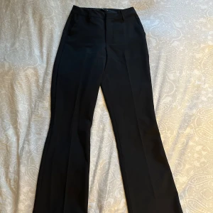 Svarta kostymbyxor från Bik Bok - Svarta kostymbyxor från Bik Bok i klassisk modell med hög midja och raka ben. Byxorna har pressveck, hällor för skärp. Använda sparsamt, ej noppriga. 