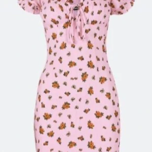 Rosa blommig kortklänning Bik Bok - Supersöt rosa kortklänning från Bik Bok med små blommor i orange och grönt. Klänningen har korta puffärmar, smockad rygg och knytning framtill vid bysten. 
