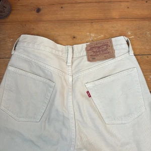 Levi's 501 ljusa jeans i bomull - Snygga ljusa Levi's 501 jeans i klassisk rak modell. Byxorna har fem fickor, knäppning med knappar och är tillverkade i bomull. Perfekt för dig som gillar en tidlös och avslappnad stil. Ikonisk läderpatch bak och röda Levi's-taggen på fickan.