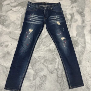 Dsquared2  jeans -  Dsquared2 jeans med snygga slitningar och färgstänk. Passform är slimfit. Storlek M. Skriv för fler funderingar