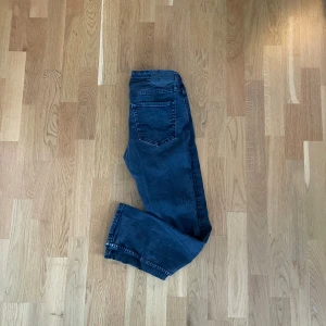 Jack and Jones Jeans - Snygga mörkblå jeansbyxor i rak passform med klassiska fem fickor och knappgylf. Jeansen har en stilren look och passar perfekt till en avslappnad outfit. Tillverkade i mjukt denimtyg som ger en bekväm känsla hela dagen.