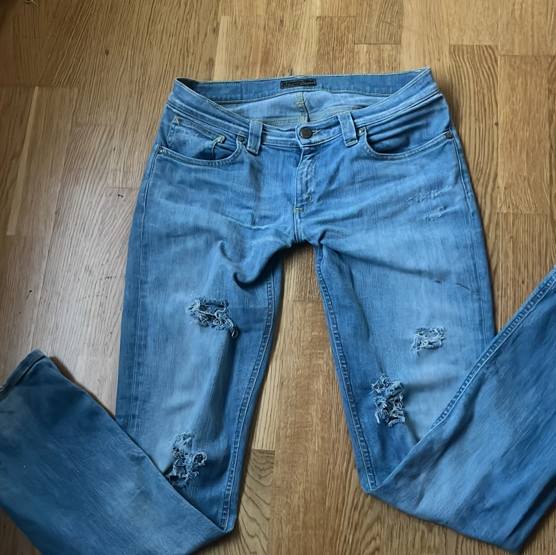 Ljusblå slitna jeans med utsvängda ben 