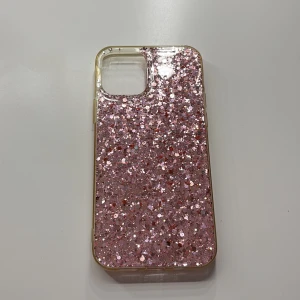 Glittrigt rosa skal till iPhone 12 - Snyggt och glittrigt rosa mobilskal med glittereffekt. Passar iPhone-modeller med stor kameramodul. Skalet är i gott skick utan synliga repor eller skador. Perfekt för dig som vill ge din telefon ett unikt och stilfullt utseende. Till iPhone 12!💗🤗