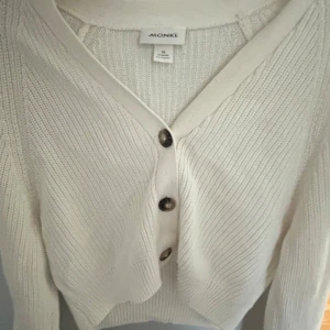 Vit stickad kofta från Monki XS - Säljer en vit stickad kofta från Monki i storlek XS. Koftan har v-ringning, tre knappar framtill och är långärmad. Den är ribbstickad och har en mjuk, skön känsla som passar perfekt till lager-på-lager. Enkel och clean design.