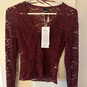 Vinröd spetsblus från Gina Tricot - Säljer en vinröd blus från Gina Tricot i spets som har ej använts och har fortfarande prislappen från! storlek xs.