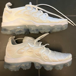 Nike Air Vapormax Plus vita sneakers - Nike Air Vapormax Plus i helvitt med genomskinlig sula. Ovandel i syntetmaterial med unika vågformade detaljer och snörning. 